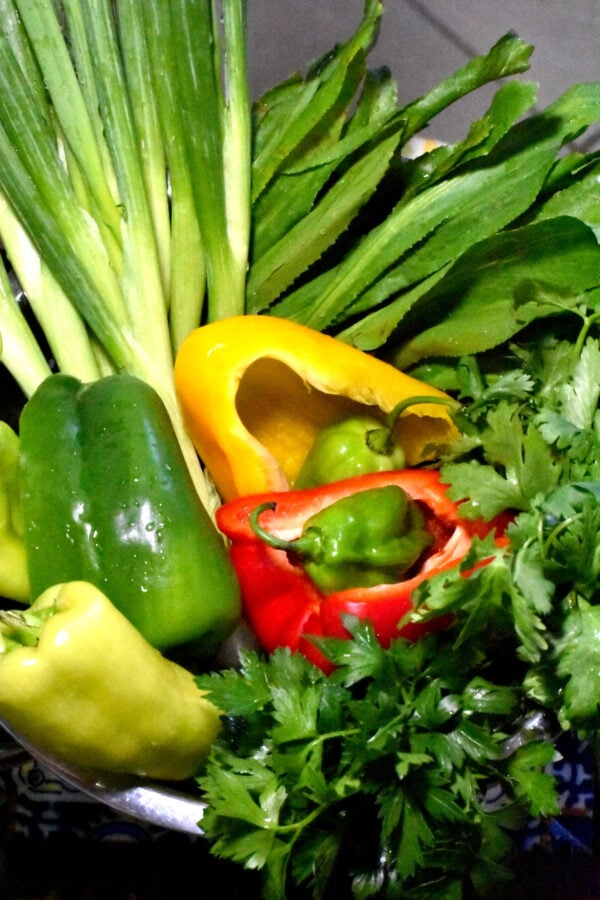 Les herbes et les légumes lavés dans une passoire.