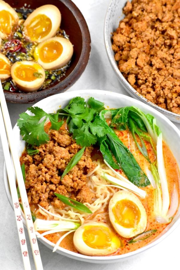 A bowl of this pink colored soup with ground pork, ramen noodles, bok choy and soft boiled eggs.