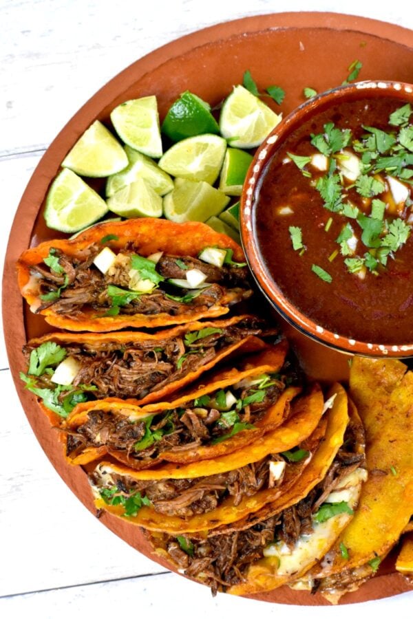 platter of birria tacos with a cup of consommé