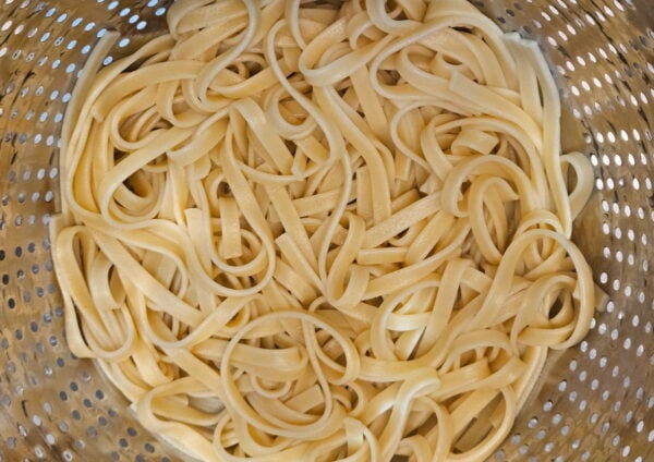 Boiled fettuccine in a colander.