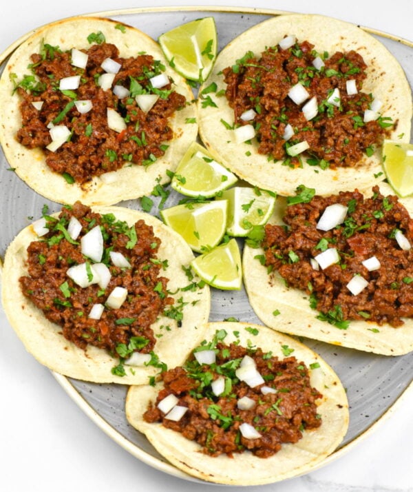 Platter of tacos filled with birria flavored ground beef.