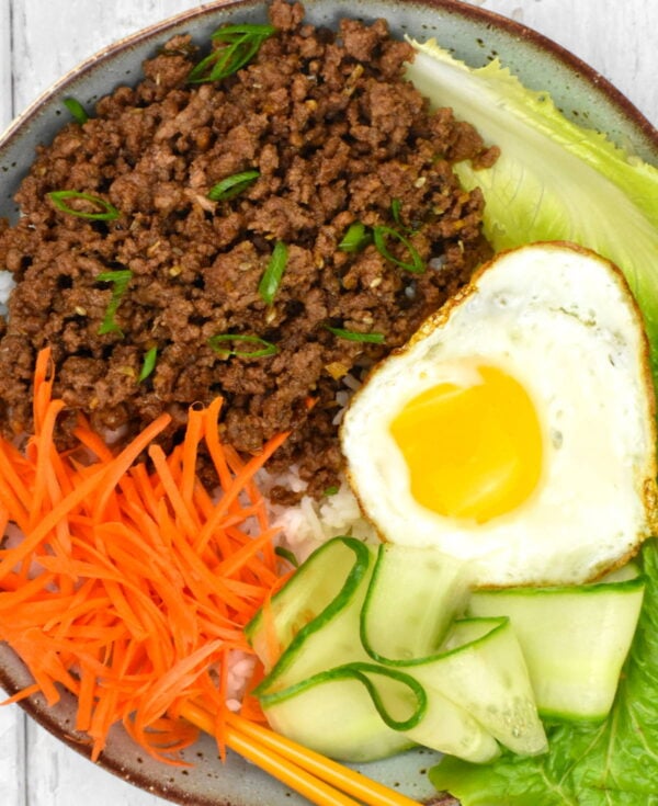 Ground beef bulgogi in a bowl with rice, vegetables and fried egg.