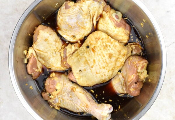 Chicken pieces marinating in soy sauce mixture.
