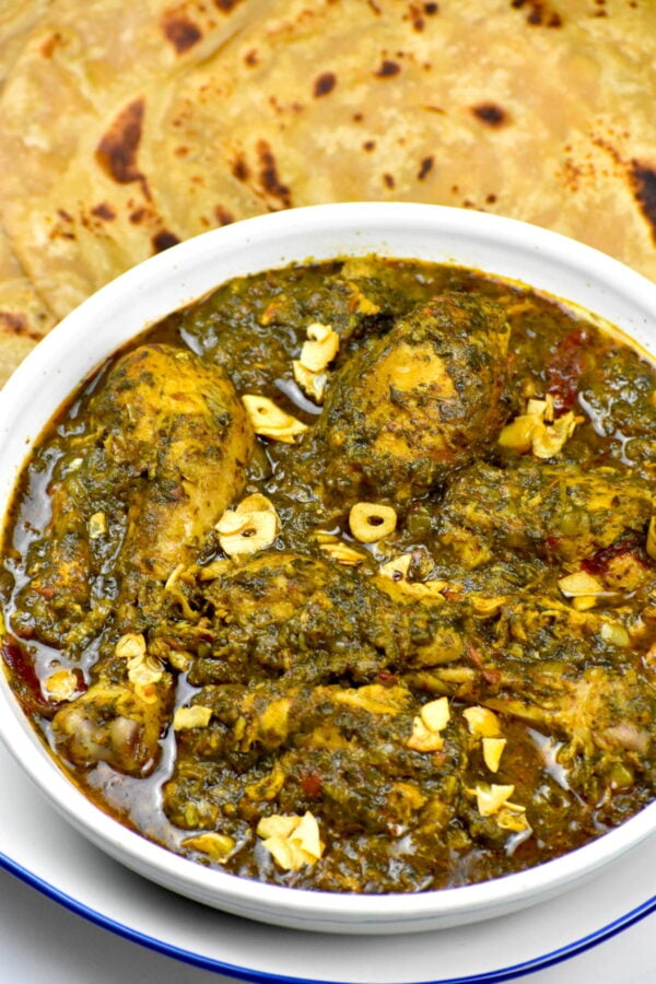 A bowl of indian chicken and spinach.