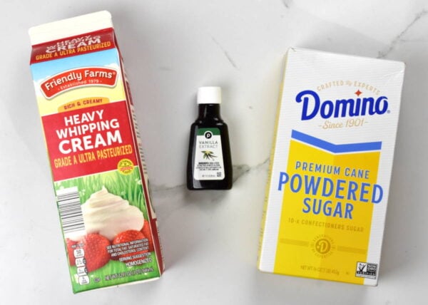 whipping cream, vanilla extract and powdered sugar on a white background.