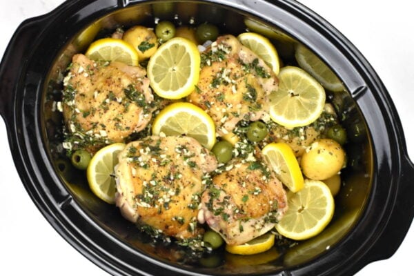 slow cooker full of chicken and potatoes before cooking.