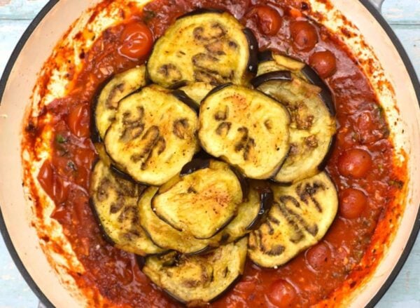 Adding eggplant to the sauce.