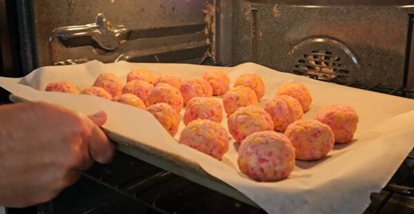Placing the sausage balls into the oven.