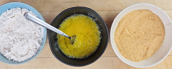 three bowls with flour, breadcrumbs and eggs