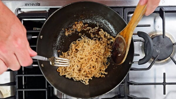 mixing the cooked noodles with the sauce