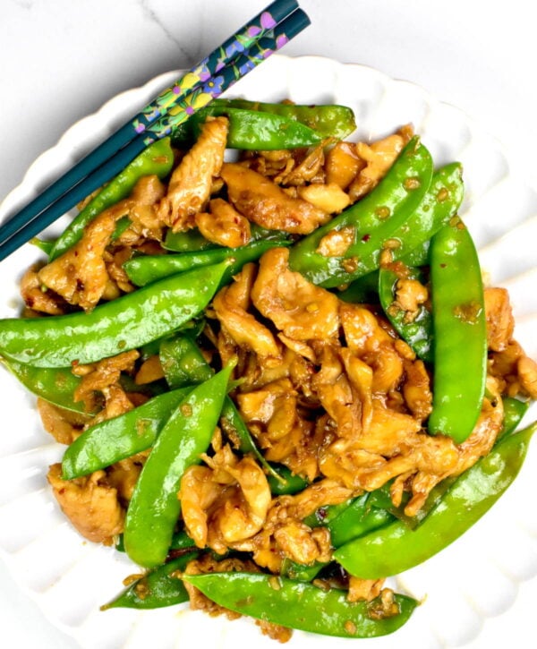 Chicken and snow peas served on a plate.