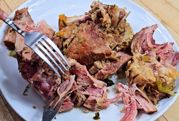 Shredding cooked ham with two forks.