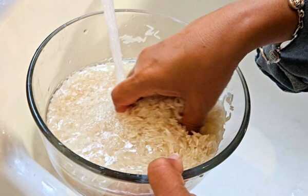 Rinsing uncooked rice in a bowl.