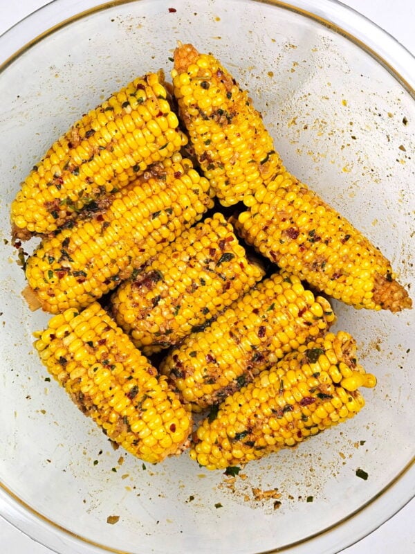 Bowl full of corn cobs with cajun butter sauce.