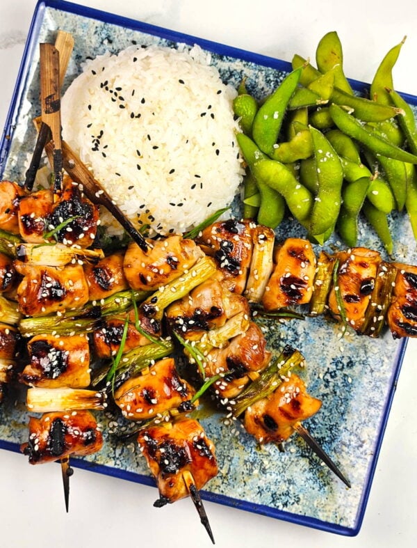 Platter of yakitori with rice and edemame.