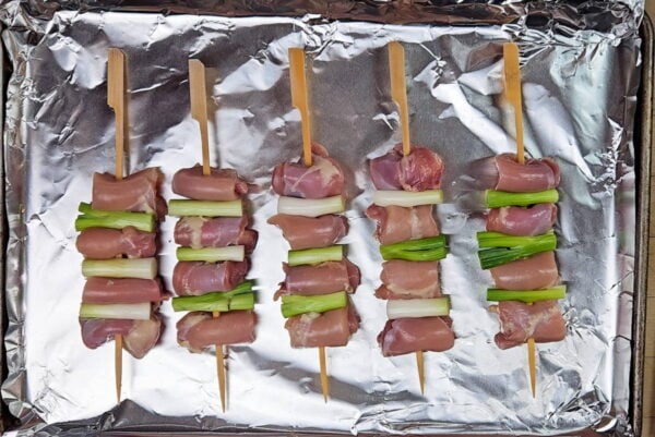 Chicken and scallion threaded onto wooden skewers.