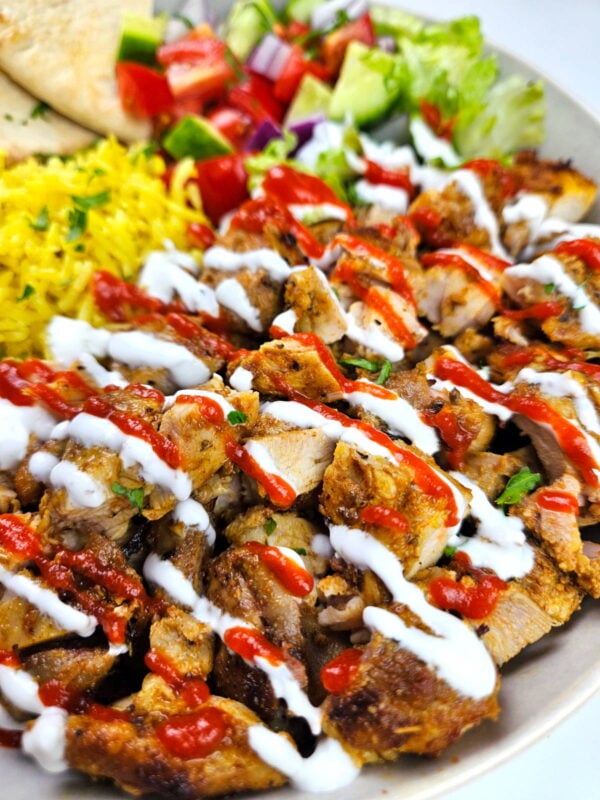 Close up shot of halal cart chicken toped with white sauce.