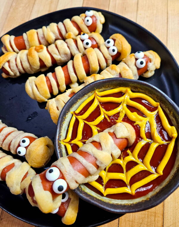 Dipping a mummy hot dog into ketchup.